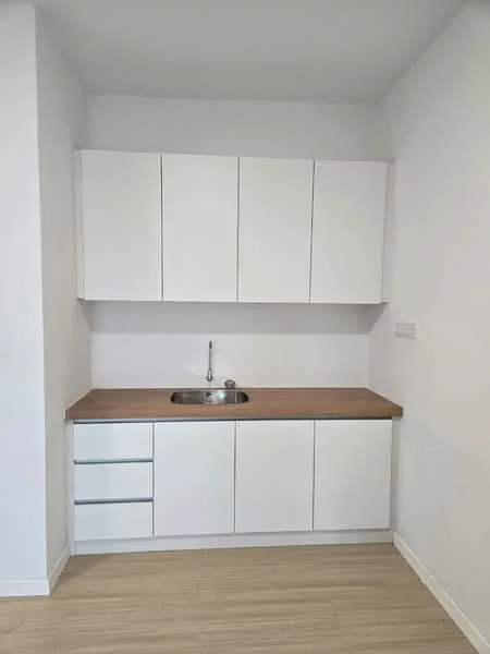 Kitchen features: white cabinetry, wood countertop, single-bowl stainless-steel sink, chrome faucet, 3 upper cabinets, 3 lower drawers, light wood flooring, plain white walls; style: modern.