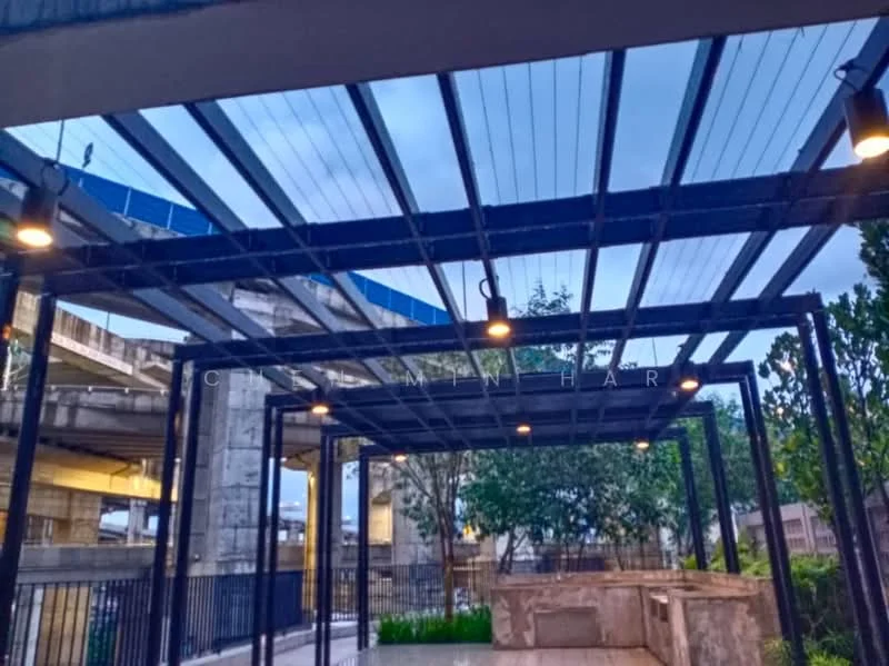 Exterior features: metal pergola structure, overhead lighting fixtures, concrete flooring, landscaped greenery, surrounding fencing, open-air design; style: modern.