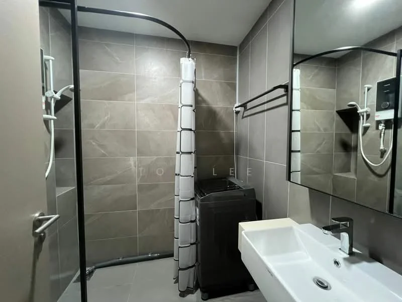 Bathroom features: grey tiled walls, grey tiled flooring, walk-in shower with glass enclosure, shower head with handheld attachment, white countertop sink, wall-mounted mirror, chrome faucet, washing machine, towel rack, curtain for shower, wall-mounted shower controls; style: modern.