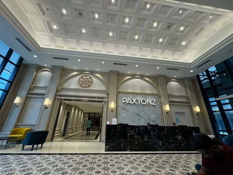 Lobby features: coffered ceiling with recessed lighting, marble reception desk, decorative wall clock, ornate wall paneling, black marble flooring, patterned floor tiles, upholstered yellow armchair, upholstered blue armchair, large glass windows, modern light fixtures; style: modern.