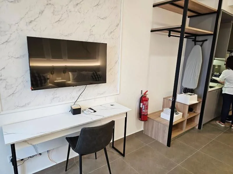 Room features: marble accent wall, flat-screen TV mounted on wall, white desk with black metal legs, black chair, open shelving unit, wooden cabinetry, fire extinguisher, iron board, grey tiled flooring, recessed lighting; style: modern.