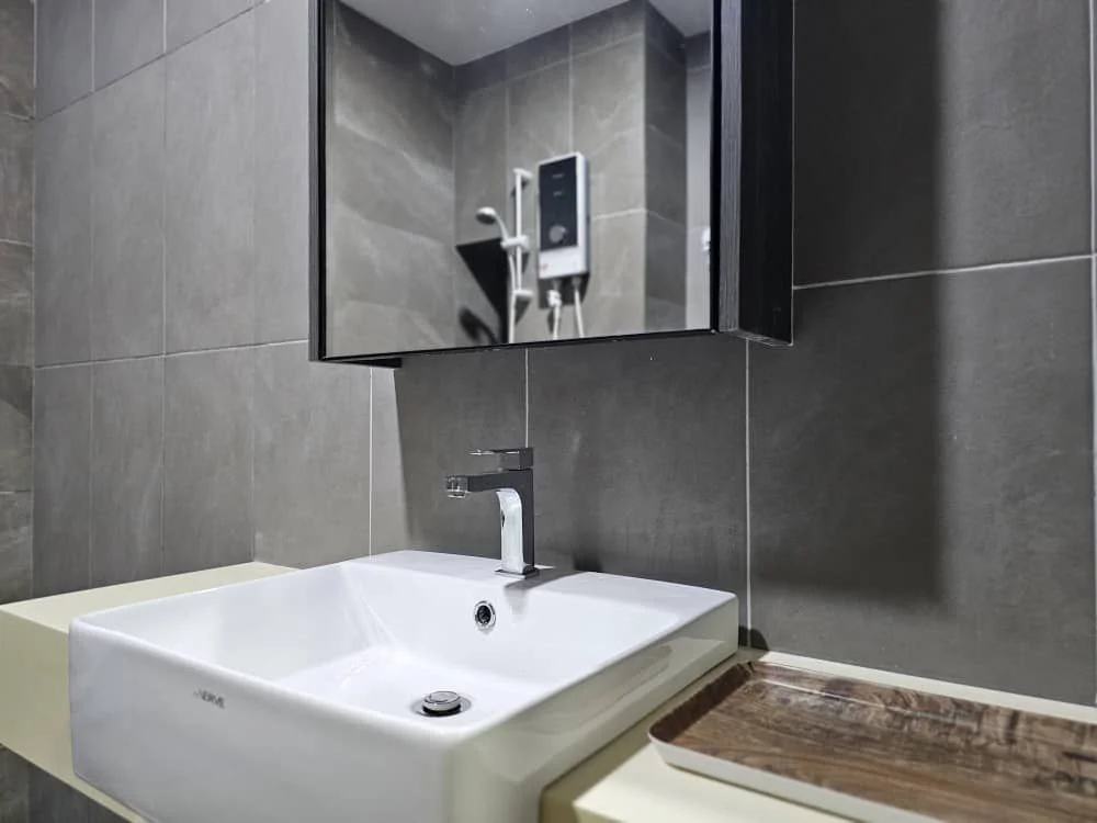 Bathroom features: white square sink, chrome faucet, wall-mounted mirror, grey tiled walls, grey tiled flooring, shower head visible, wall-mounted shower control, wooden tray; style: modern.