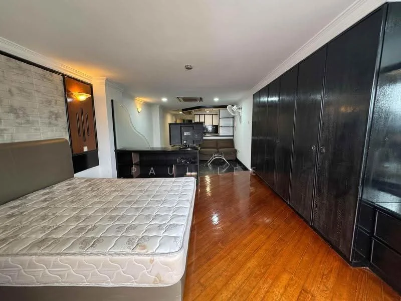 Bedroom features: wooden flooring, grey accent wall, built-in wardrobe with black finish, queen-size bed frame, recessed ceiling lights, wall-mounted TV, open layout to kitchen area, large window for natural light; style: modern. Kitchen features: open kitchen layout, kitchen island, stainless-steel sink, built-in cabinets, exhaust hood, countertop with space for appliances; style: modern.
