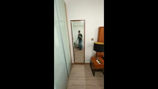 Room features: wooden flooring, full-length mirror, table lamp, nightstand, white walls, sliding glass door, decorative wall panel, window, minimalist decor; style: modern.