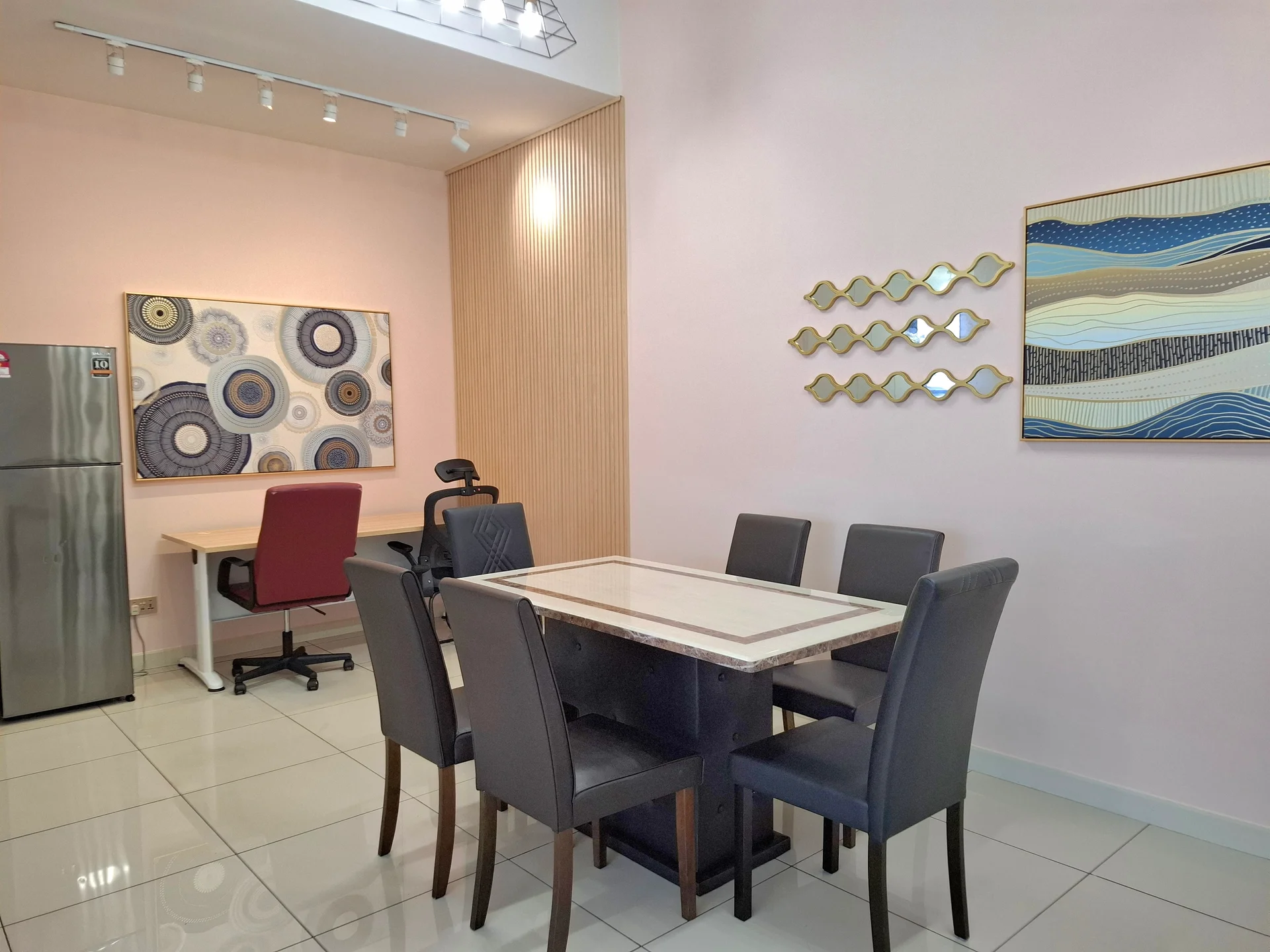 Dining features: 6-seater dining table with marble top, upholstered dining chairs in black, white tiled flooring, pink painted walls, wood panel accent wall, framed artwork on wall, decorative wall mirrors, recessed ceiling lights; style: modern. Study features: desk with chair, white desk surface, black office chair, wall-mounted artwork; style: modern.