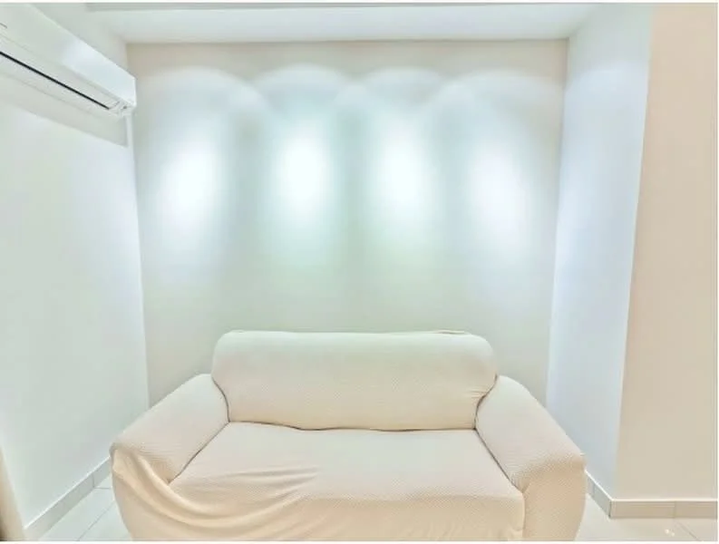 Room features: white painted walls, sofa with slipcover, wall-mounted split AC, recessed lighting, tile flooring; style: modern.