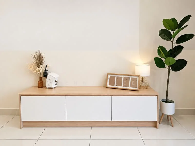 Room features: white cabinetry with wooden top, decorative vase with dried flowers, table lamp with white shade, framed artwork or photos, green potted plant, white tiled flooring, neutral wall color; style: modern.