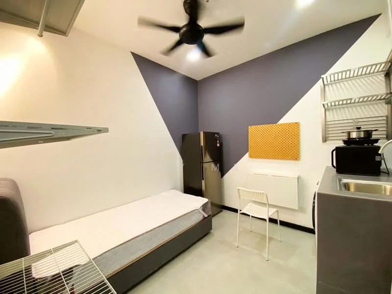 Bedroom features: single bed with mattress, grey upholstered bed frame, white painted walls, accent wall in dark blue, ceiling fan with 5 blades, stainless-steel fridge, white wall-mounted air conditioning unit, metal shelving unit, kitchenette with sink, white chair; style: modern.