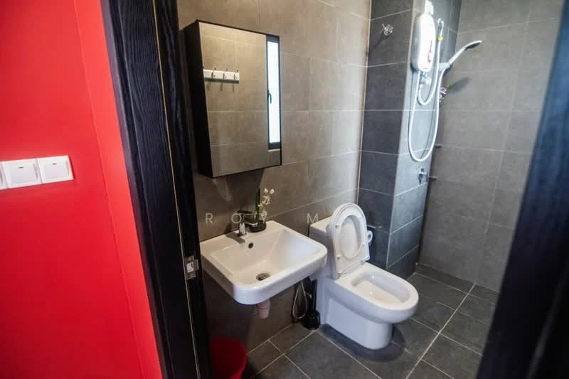 Bathroom features: grey tiled walls, dark grey tiled flooring, white wall-mounted sink, chrome basin mixer faucet, white toilet, shower area with glass partition, handheld shower head, water heater unit, mirror with black frame, towel rack, plant decoration; style: modern.