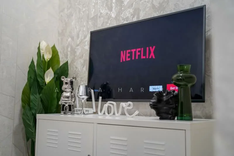 Room features: wall-mounted TV, decorative vases, glassware, decorative figurines, white cabinet, green plant, decorative sign with the word 'love', textured wall finish; style: modern.