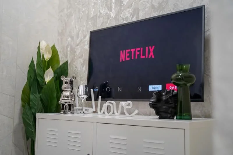 Living features: wall-mounted TV, decorative plant, glass vase, decorative figurine, white storage cabinet, decorative word art, black decorative sculpture, silver wine glass; style: modern.