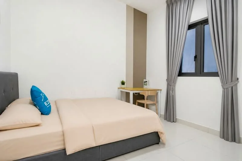 Bedroom features: queen-size bed with beige bedding, grey upholstered bed frame, white painted walls, light grey accent wall, floor-to-ceiling window, black framed window, sheer curtains, small desk with chair, decorative plant on desk, tile flooring, wall-mounted light fixture; style: modern.