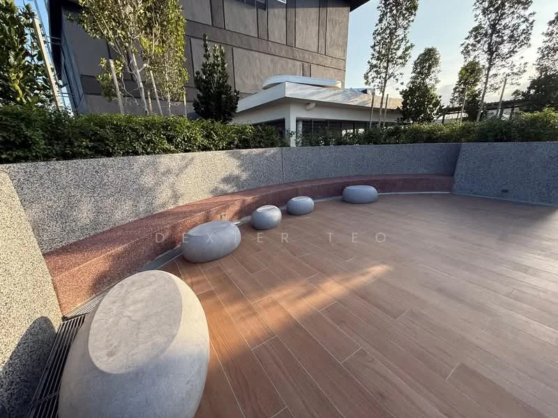 Exterior type: landscape garden; features: textured stone seating, wooden decking, low stone wall, landscaped greenery, paved walkway, modern architectural backdrop, outdoor seating area; style: modern.