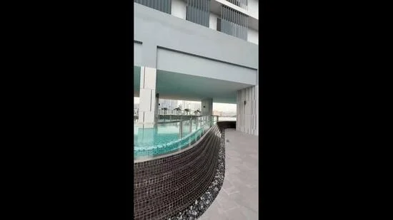 Exterior type: high-rise condominium; features: infinity pool, glass railing, stone-paved walkway, landscaped garden, modern architectural design, outdoor seating area, water feature, pool deck with loungers; style: modern.