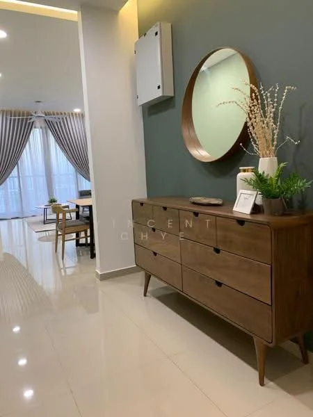 Room features: wooden sideboard with drawers, round mirror, green accent wall, cream painted walls, marble tile flooring, curtains in neutral color, decorative vase with dried flowers, small decorative items on sideboard, dining table visible in background, chairs visible in background, recessed ceiling lights; style: modern.