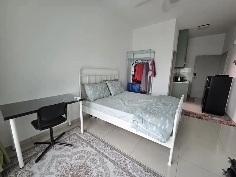 Bedroom features: queen-size bed with grey bedding, white metal bed frame, study desk with black chair, light grey walls, white ceiling, floor-to-ceiling windows, ceramic tile flooring, wardrobe rack with clothes, refrigerator, kitchenette area with cabinets; style: modern.