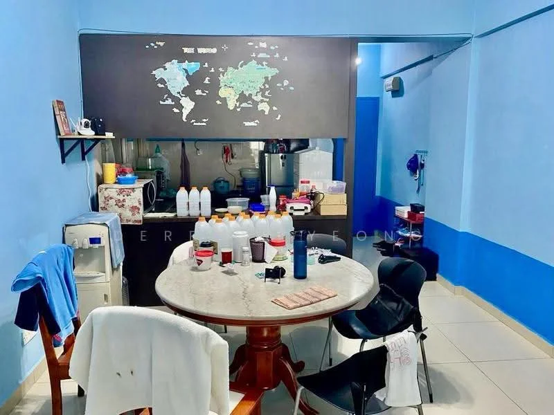 Dining features: round dining table, wooden dining chairs, blue painted walls, white tiled flooring, map wall decor, refrigerator, kitchen area visible in background, countertop with various containers, water dispenser, shelves with kitchen items.