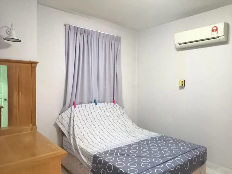 Bedroom features: queen-size bed with patterned bedding, wooden headboard, white painted walls, curtains in light grey, 1 wall-mounted split AC, wooden dresser, area rug with circular pattern, light fixture on wall.