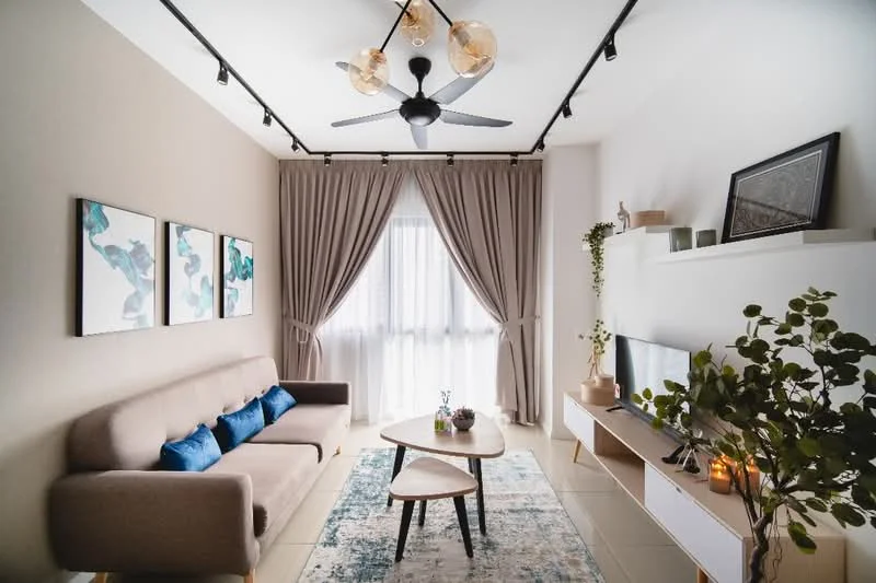 Living features: 3-seater fabric sofa in beige, blue decorative cushions, coffee table with wooden top, area rug with abstract pattern, wall-mounted TV, white TV console, floor-to-ceiling windows, sheer curtains, 5-blade ceiling fan with light, track lighting, framed artwork on walls, decorative plant in pot; style: modern.