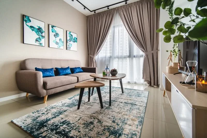 Living features: 3-seater fabric sofa in beige, blue decorative cushions, 2 round coffee tables in wood, area rug with abstract pattern, floor-to-ceiling windows, sheer curtains, wall-mounted TV, decorative plant, framed artwork with blue tones, light-colored wall, recessed ceiling lights; style: modern; view: city.