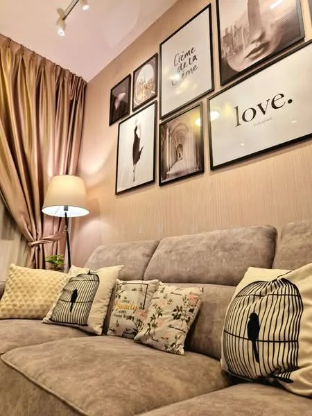 Living features: 3-seater fabric sofa in grey, decorative pillows with birdcage design, decorative pillows with floral pattern, wall-mounted artwork in frames, curtains in beige, table lamp with fabric shade, textured wall with light color, recessed ceiling lights; style: modern.