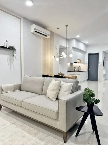 Living features: 3-seater fabric sofa in light grey, decorative throw pillow, black side table, wall-mounted air conditioning unit, recessed LED downlights, pendant lighting with multiple bulbs, light-colored tiled flooring, light grey accent wall, wood paneling on one wall, open kitchen area in background; style: modern.