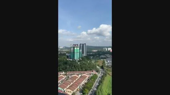 Exterior type: high-rise condominium; features: glass curtain wall, green facade, surrounded by greenery, urban skyline view, multiple storeys, adjacent to residential area; style: modern.