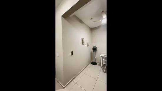 Room features: light grey painted walls, white ceiling, tile flooring, ceiling fan, wall-mounted light switch, decorative wall art, small table, floor fan; style: modern.