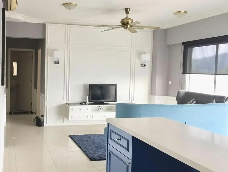Living features: light grey painted walls, white wainscoting, glossy white tile flooring, 5-blade ceiling fan with light, wall-mounted TV, built-in TV console with storage, blue fabric sofa, area rug with geometric pattern, large windows with black roller blinds, decorative cushions, recessed lighting; style: modern. Room features: doorway leading to hallway, light grey painted walls, white trim.