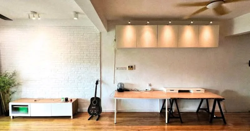Living features: white painted walls, exposed brick wall, wooden flooring, 5-blade ceiling fan, track lighting, wooden table, black guitar, white console table with green accent, shelves with recessed lighting; style: modern.