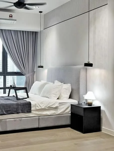 Bedroom features: king-size bed with upholstered headboard, white bedding with multiple pillows, bedside table in black, table lamp on bedside table, grey throw blanket, floor-to-ceiling windows, grey curtains, wooden flooring, 5-blade ceiling fan, wall-mounted air conditioning unit, decorative plant on bedside table; style: modern; view: city.