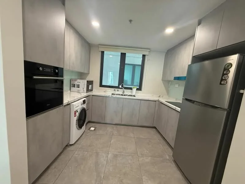 Kitchen features: grey cabinetry, white countertop, stainless-steel fridge, built-in oven, microwave, washing machine, single-bowl stainless-steel sink, chrome pull-down faucet, tile flooring, recessed downlights, window with view, modern design; style: modern.