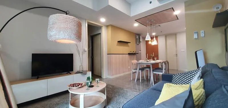 Living features: grey fabric sofa, round coffee table, TV console, wall-mounted TV, area rug, pendant lamp, decorative wall paneling, recessed ceiling lights, dining table with chairs, open-plan layout; style: modern.