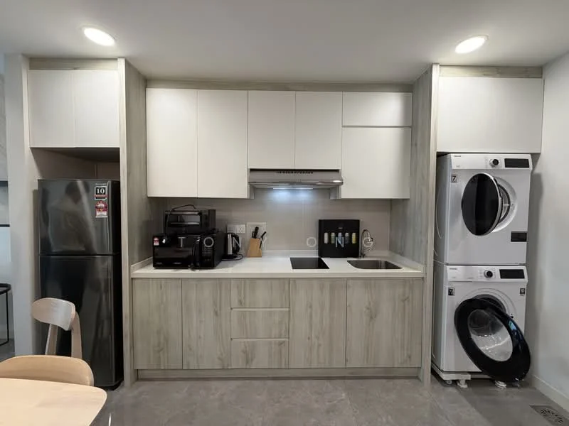 Kitchen features: white upper cabinets, light wood lower cabinets, black countertop, stainless-steel sink, chrome pull-down faucet, built-in stove, built-in oven, stainless-steel side-by-side fridge, black coffee machine, stacked washer and dryer, grey tile flooring, recessed downlights; style: modern.