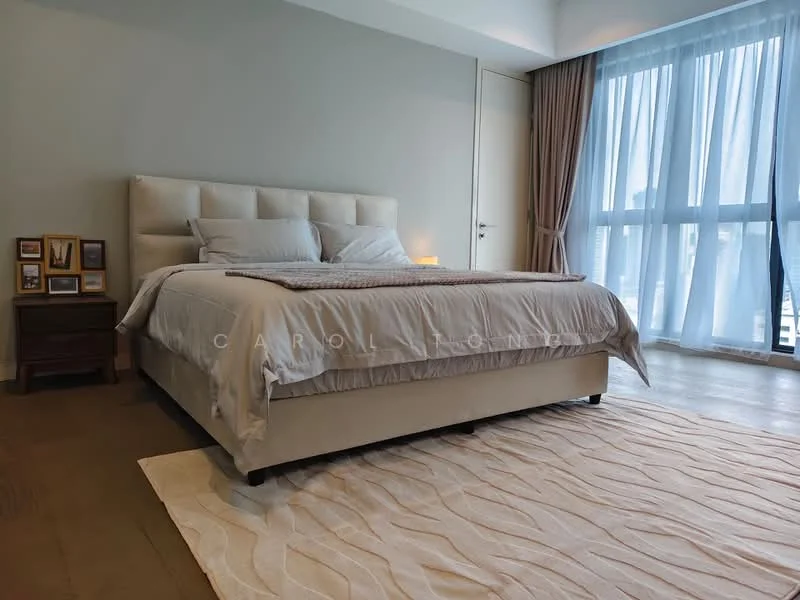 Bedroom features: king-size bed with upholstered headboard, bedding in neutral tones, two bedside tables, framed photographs on bedside table, large floor-to-ceiling windows, sheer curtains, wooden flooring, area rug with geometric pattern, wall-mounted light fixture; style: modern.