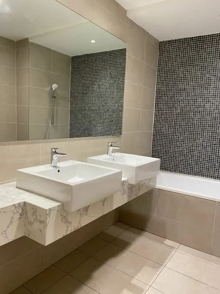 Bathroom features: double-sink vanity with marble countertop, square ceramic sinks, chrome basin mixers, large wall mirror, shower with handheld shower head, bathtub, tile flooring, light beige wall tiles, black mosaic accent wall, recessed lighting; style: modern.