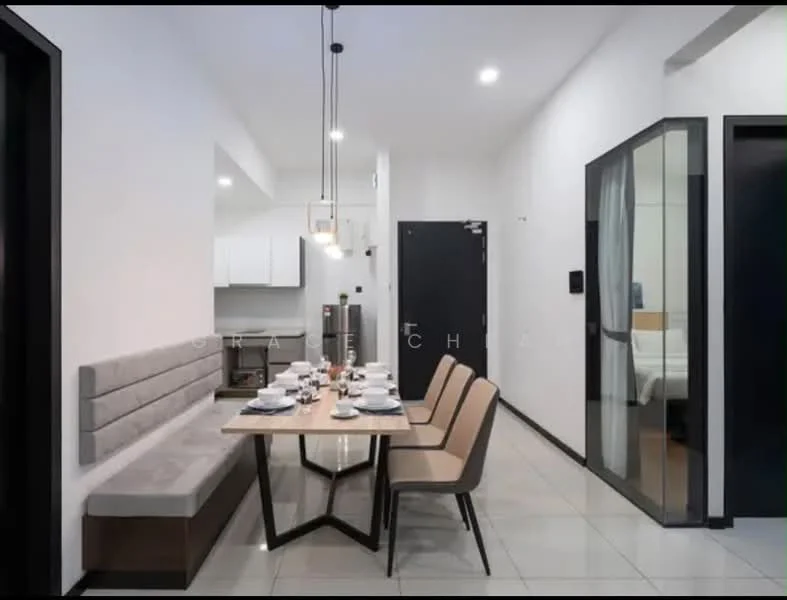 Dining features: rectangular wooden dining table, upholstered dining chairs, grey upholstered bench seating, white ceramic dinnerware, glass water glasses, cutlery, pendant lighting above table, white walls, tile flooring, wall-mounted intercom, door leading to hallway, open kitchen area visible; style: modern. Room features: white painted walls, glass door, black door, visible bedroom area.