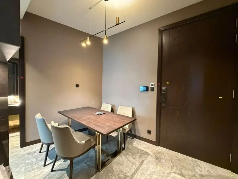 Dining features: wood dining table, 4 upholstered dining chairs in light grey, pendant lighting with three bulbs, dark brown accent wall, light grey marble flooring, wall-mounted intercom panel, door with modern handle, decorative wall paneling; style: modern.