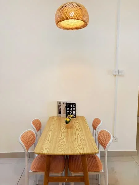 Dining features: wooden dining table, 6-seater dining table, woven pendant light, white chairs with orange cushions, decorative flower vase, book on table, cream painted walls, tile flooring; style: modern.
