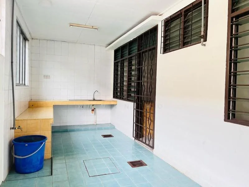 Laundry features: blue ceramic tile flooring, white tiled walls, wooden countertop, single-bowl stainless-steel sink, metal faucet, window with metal grilles, sliding metal door, drainage grate on floor, blue plastic bucket.
