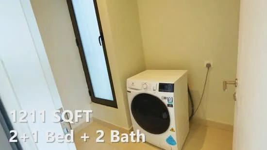 Laundry features: front-load washing machine in white, cream painted walls, tile flooring, window with black frame, power outlet, light switch.