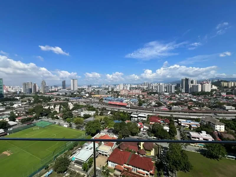 Exterior type: high-rise condominium; features: city skyline view, surrounded by greenery, open space with sports field, urban landscape, clear blue sky, multiple high-rise buildings, train tracks visible; style: modern.