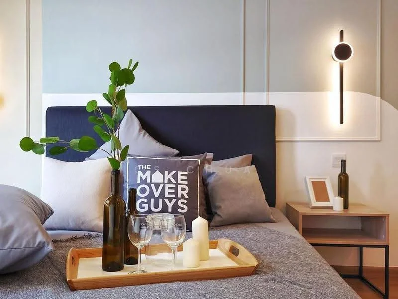 Bedroom features: king-size bed with dark upholstered headboard, grey bedding, decorative throw pillows, wooden bedside table, modern wall sconce, glass vase with greenery, tray with wine glasses and candles, textured wall paneling, neutral wall color, wooden flooring; style: modern.