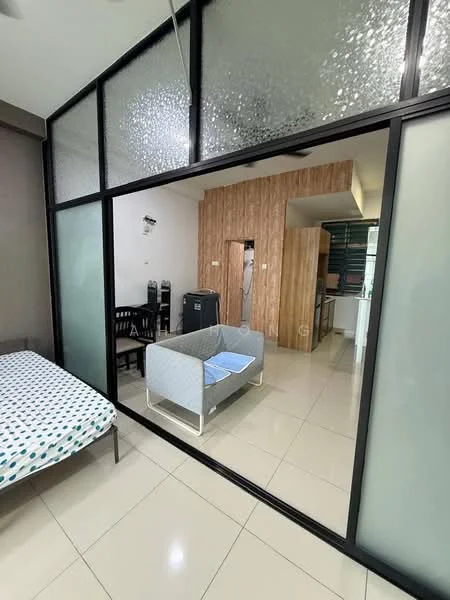 Room features: glass partition wall, grey tiled flooring, white walls, sofa with light grey upholstery, dining table with black chairs, kitchen area visible in background, refrigerator, wood panel accent wall, ceiling fan, light fixtures, bed with blue polka dot bedding; style: modern.
