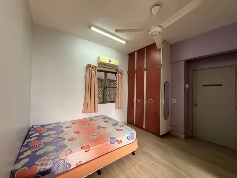 Bedroom features: single bed with colorful heart-patterned bedding, built-in wardrobe with wooden finish, window with decorative grille, curtains in light brown, ceiling fan, light-colored laminate flooring, air conditioning unit mounted on wall, painted walls in light purple; style: modern.