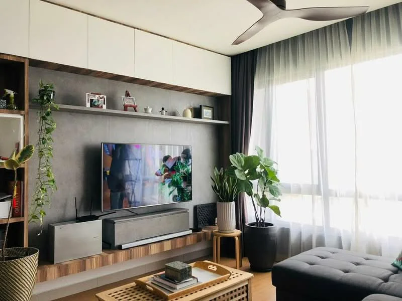Living features: 5-blade ceiling fan with light, wall-mounted TV, TV console, grey accent wall, wooden shelving unit, decorative plants, large windows with sheer curtains, coffee table, sofa with tufted design, decorative items on shelves; style: modern; view: city.