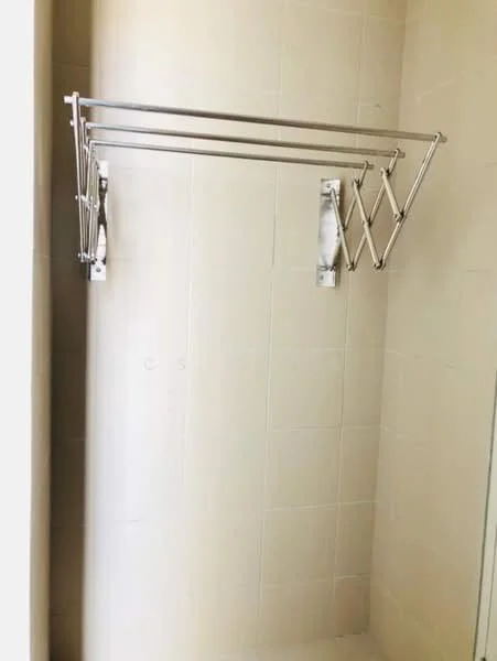 Room features: folding clothes drying rack, stainless steel, mounted on wall, light beige tiled walls.