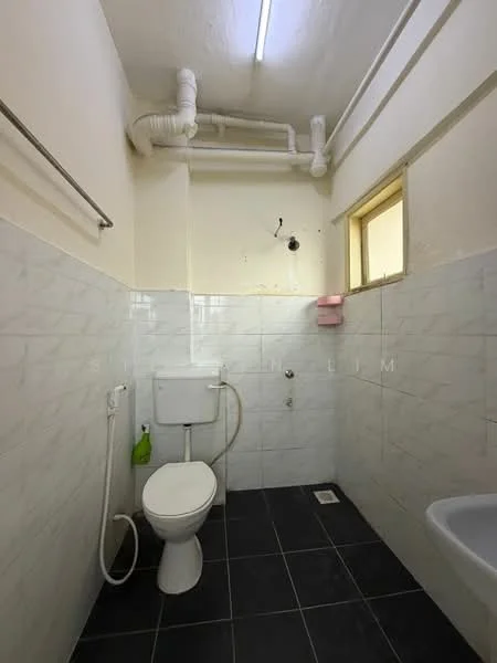 Bathroom features: white tiled walls, black tile flooring, one-piece toilet, wall-mounted faucet, shower hose, small window, exposed plumbing, soap holder.