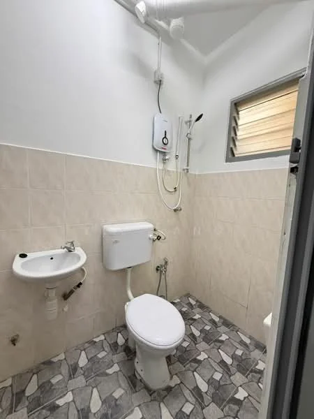 Bathroom features: white toilet, wall-mounted sink, shower with wall-mounted faucet, water heater, grey and white patterned floor tiles, cream tiled walls, window with horizontal slats, exposed plumbing.