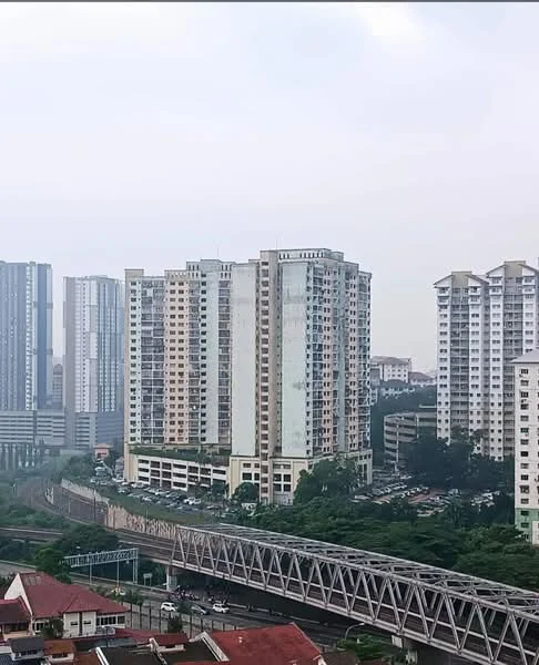 Exterior type: high-rise condominium; features: glass curtain wall, approximately 15-storey high-rise, surrounded by mature greenery, parking area visible, adjacent to highway, urban context with nearby buildings; style: modern.